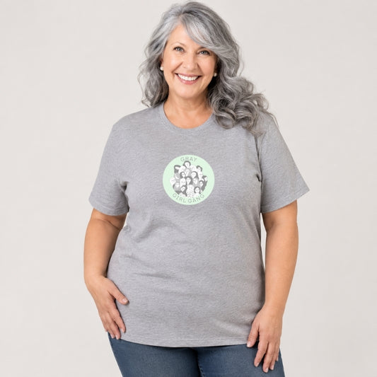 MULHER PLUS SIZE COM CAMISETA CINZA MESCLA COM DESENHO EXCLUSIVO DA LOJA CONCEITO ORGULHO GRAY: UM CÍRCULO VERDE-ÁGUA COM DESENHO DE VÁRIAS MULHERES GRISALHAS ESTILIZADAS DE TODOS OS TIPOS  E A FRASE GRAY GIRL GANG 